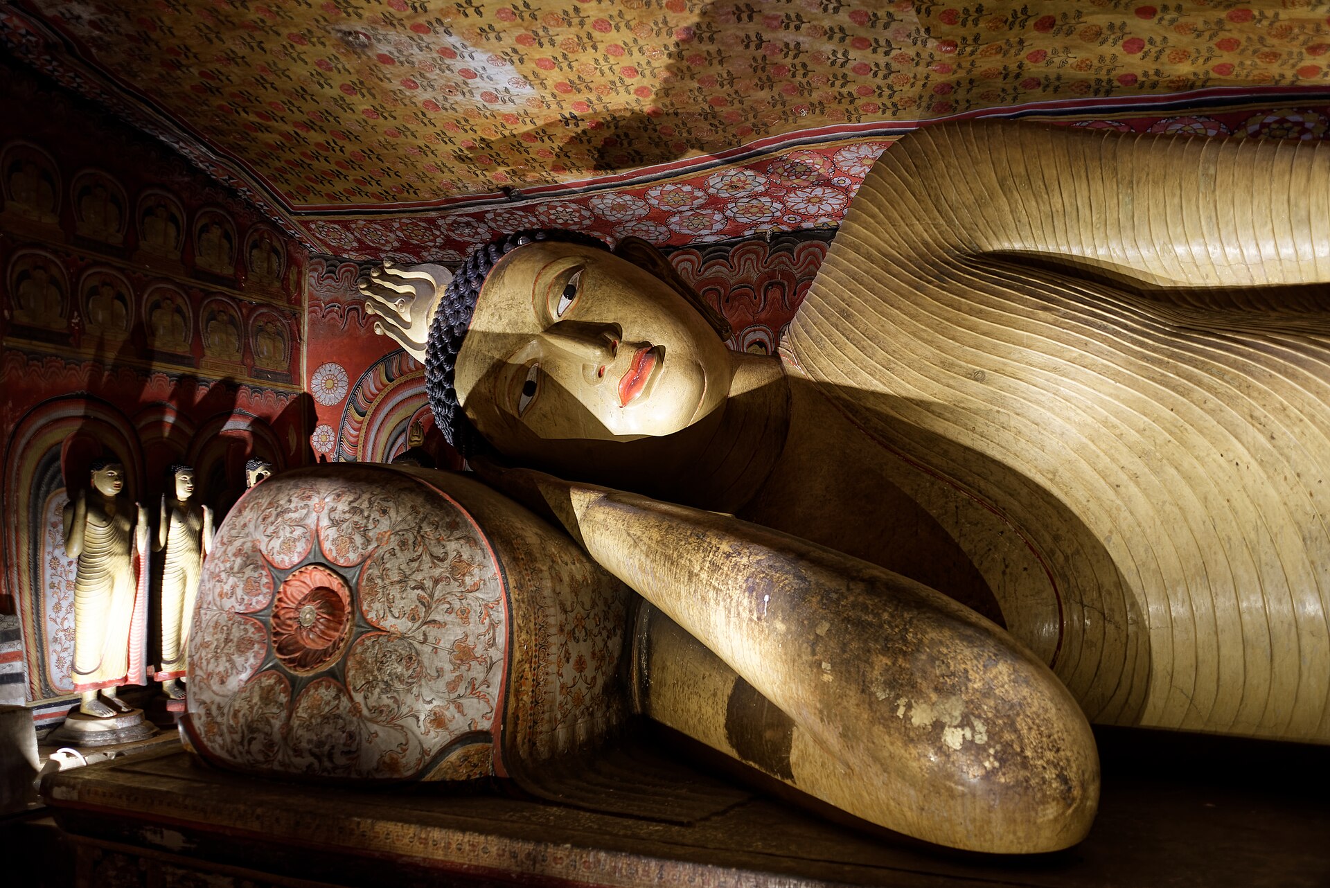 Rows of seated Buddha statues beneath painted rock ceilings in the Dambulla cave temple
