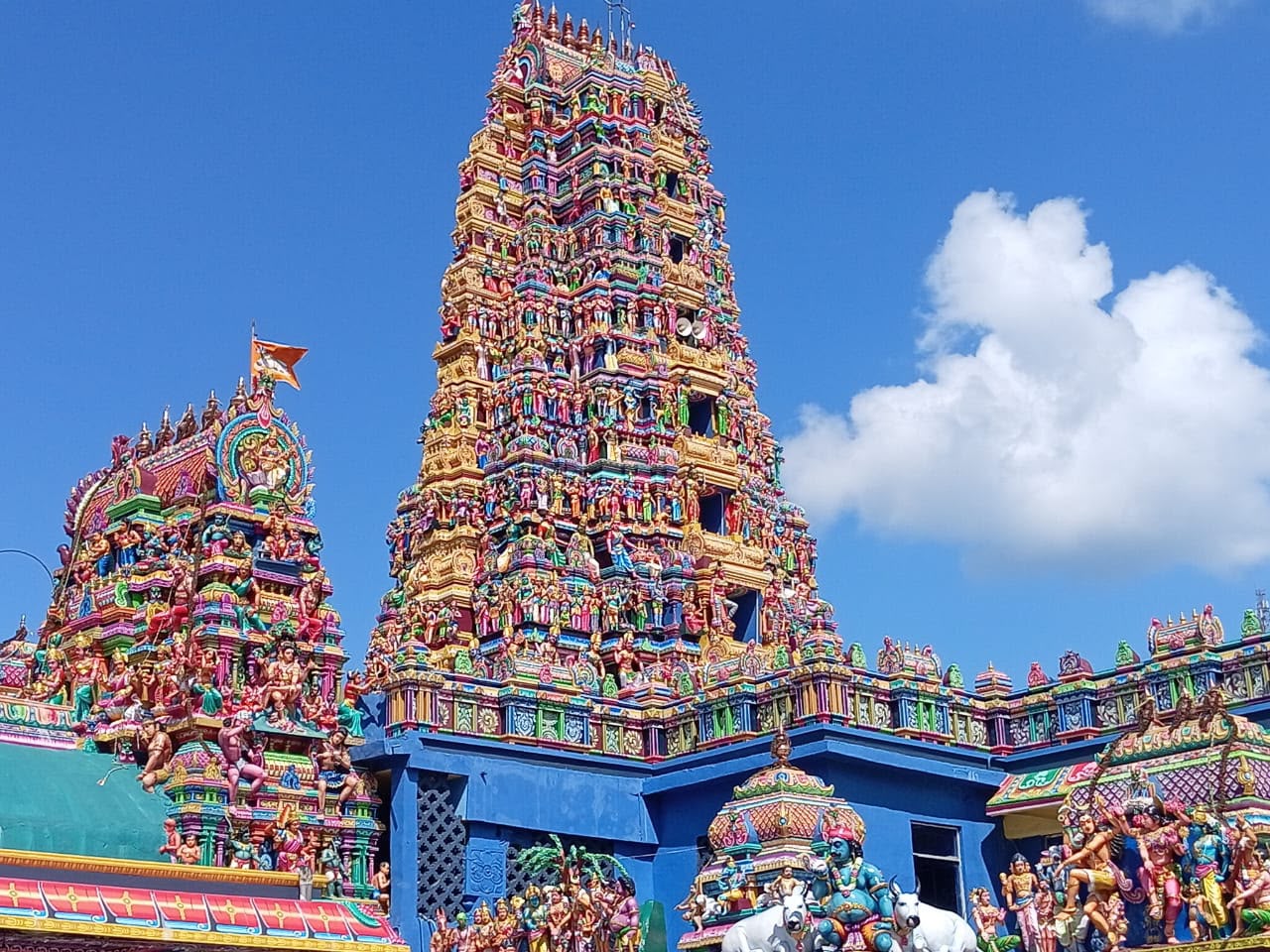 The gopuram of a Hindu kovil, its tiers densely packed with brightly painted sculpted figures
