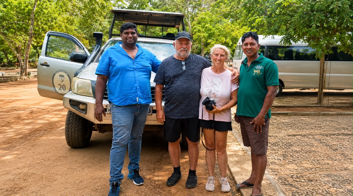 Two Mathew Tours guides with guests beside the safari jeep and the tour van