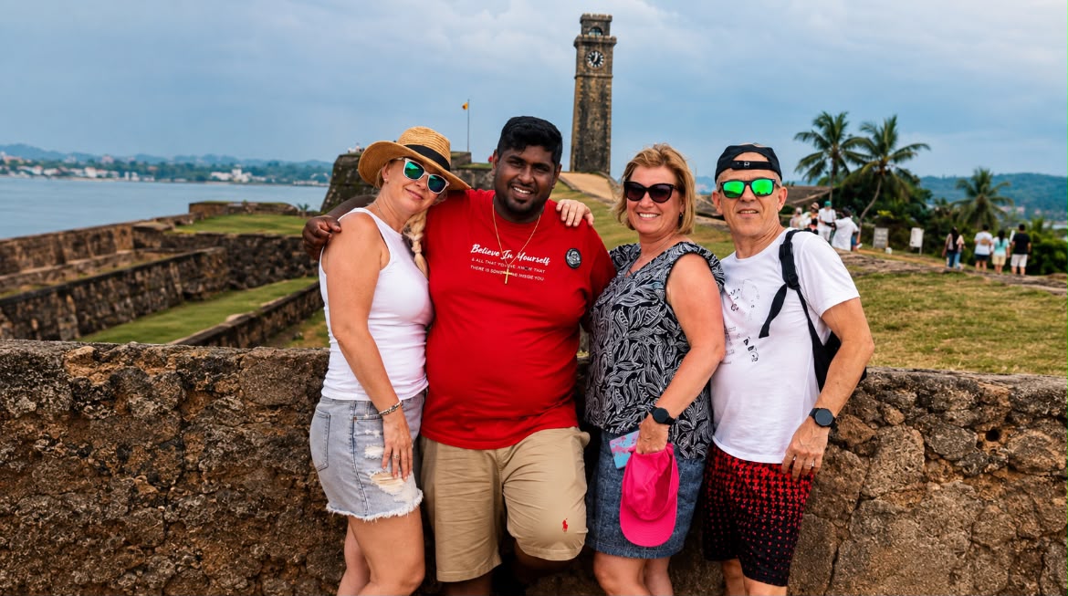 A Mathew Tours guide with guests on the ramparts of Galle Fort, the clock tower behind them