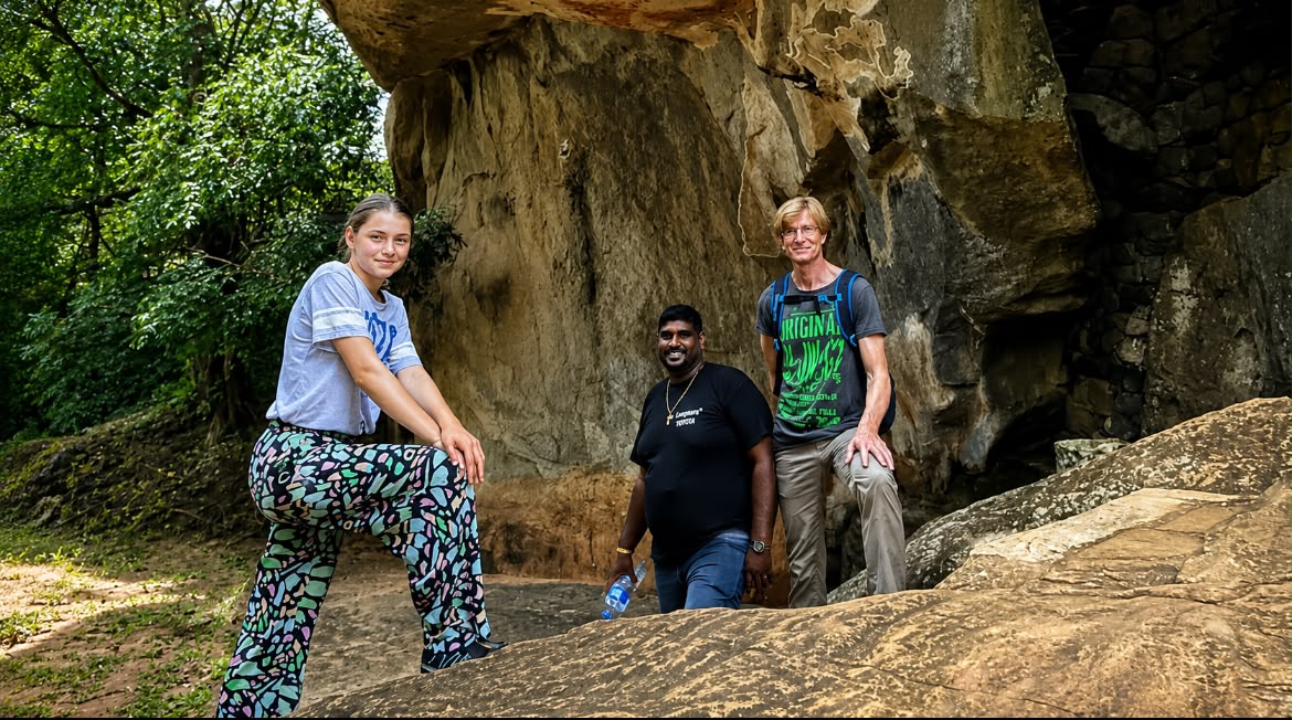 A Mathew Tours guide and two guests on the boulders beneath a rock overhang